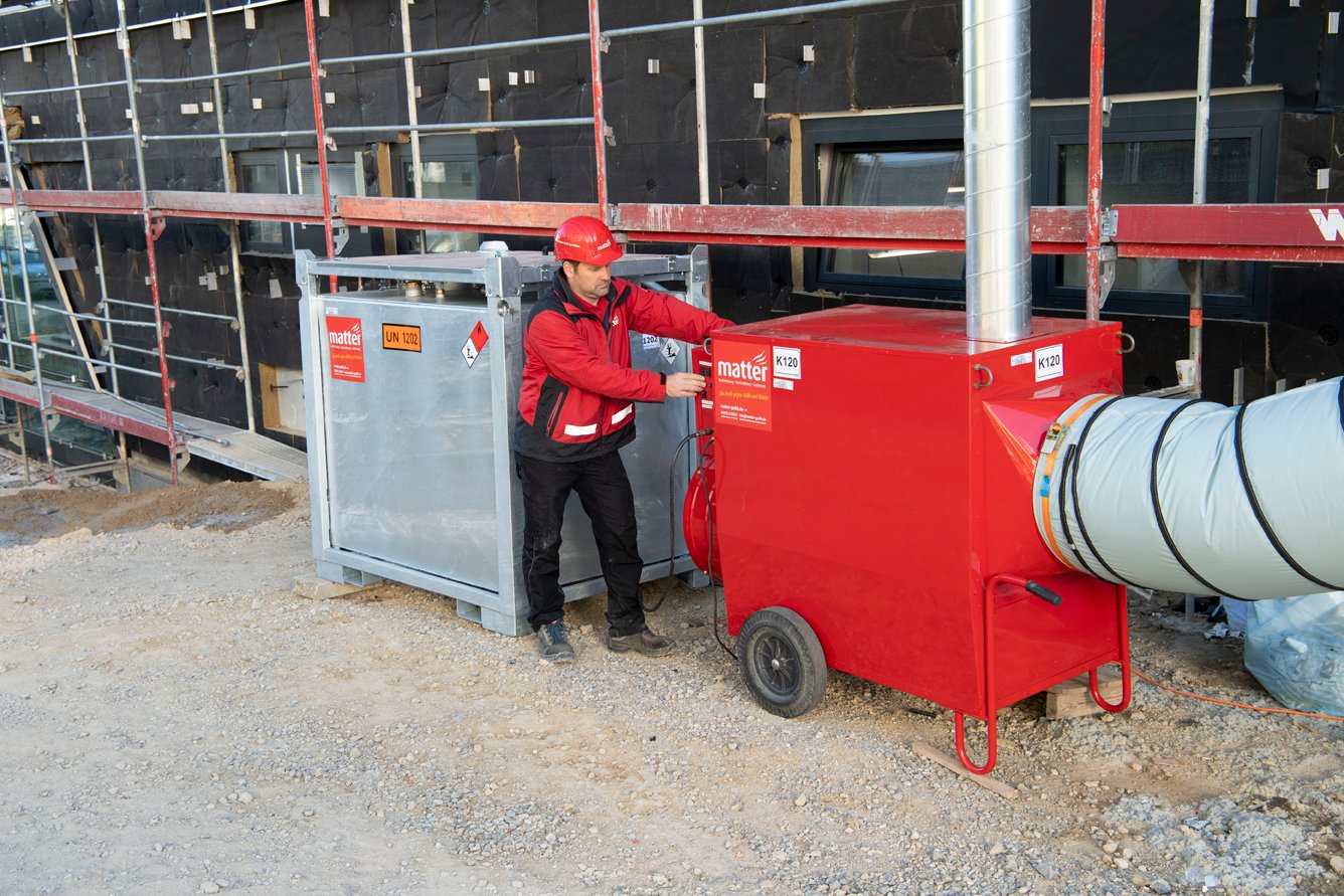 Ein roter Warmlufterzeuger der Marke Bautrocknung matter auf einer Baustelle